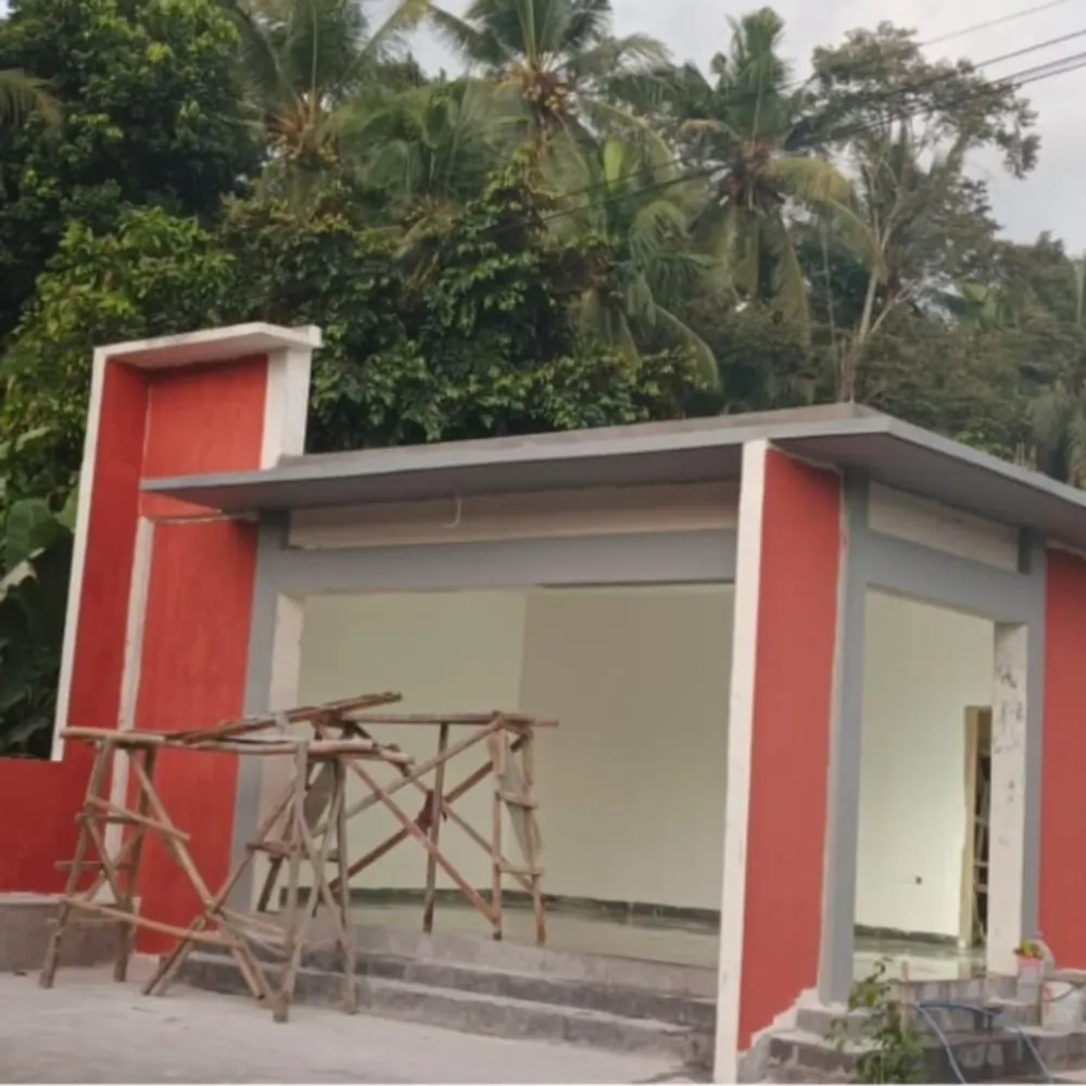 Single-storey building with red and grey facade and timber scaffolding in front