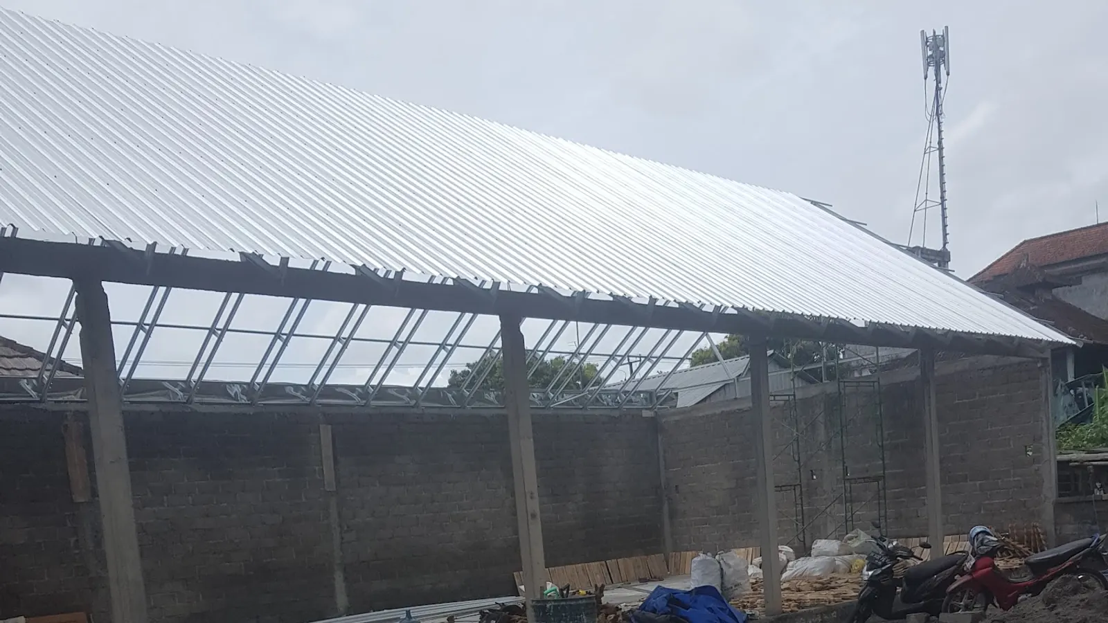 Light steel roof trusses with metal roofing over block walls on a building site